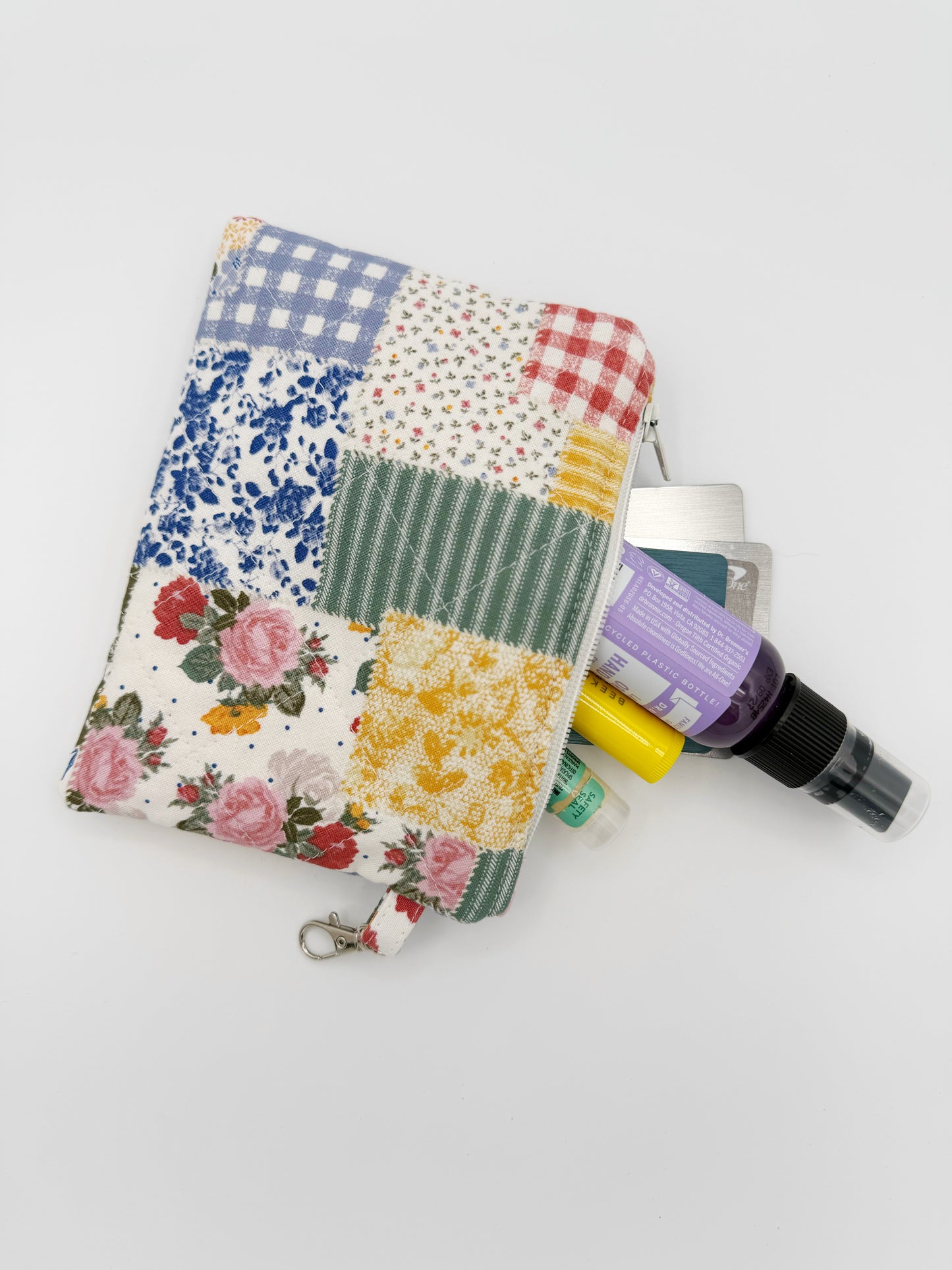 Patchwork-style pouch with floral and plaid patterns on a light gray background