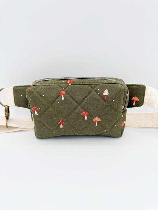Green quilted fanny pack with mushroom pattern on a light gray background