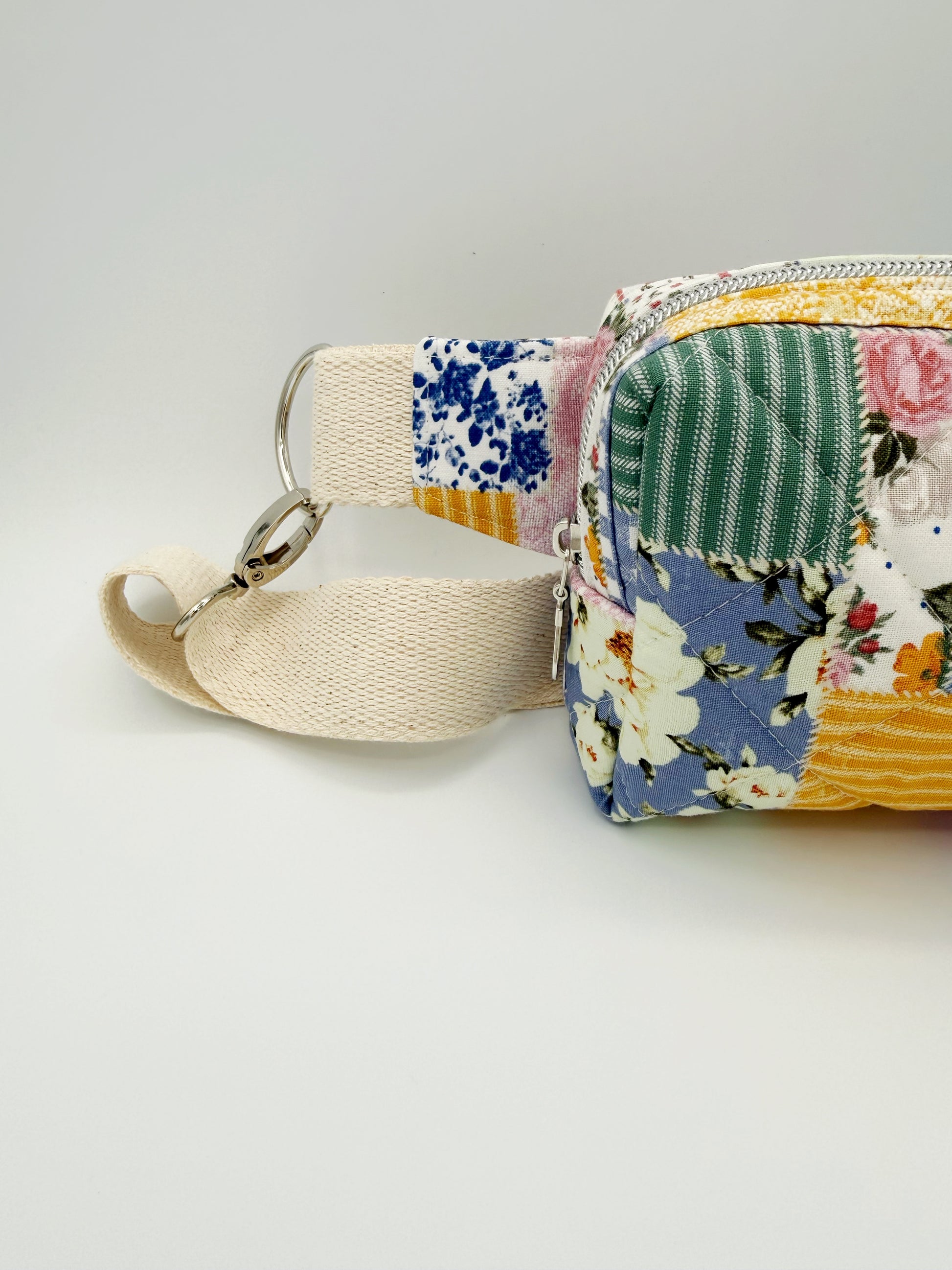 Small fabric pouch with floral and patchwork design on a light gray background left side view