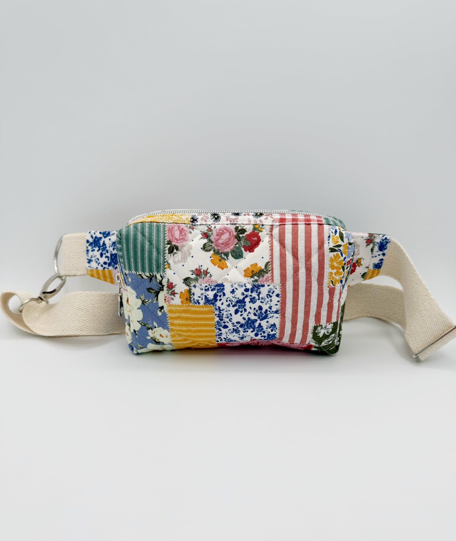 Patchwork-style crossbody fanny pack style bag with floral and striped patterns on a light gray background front view