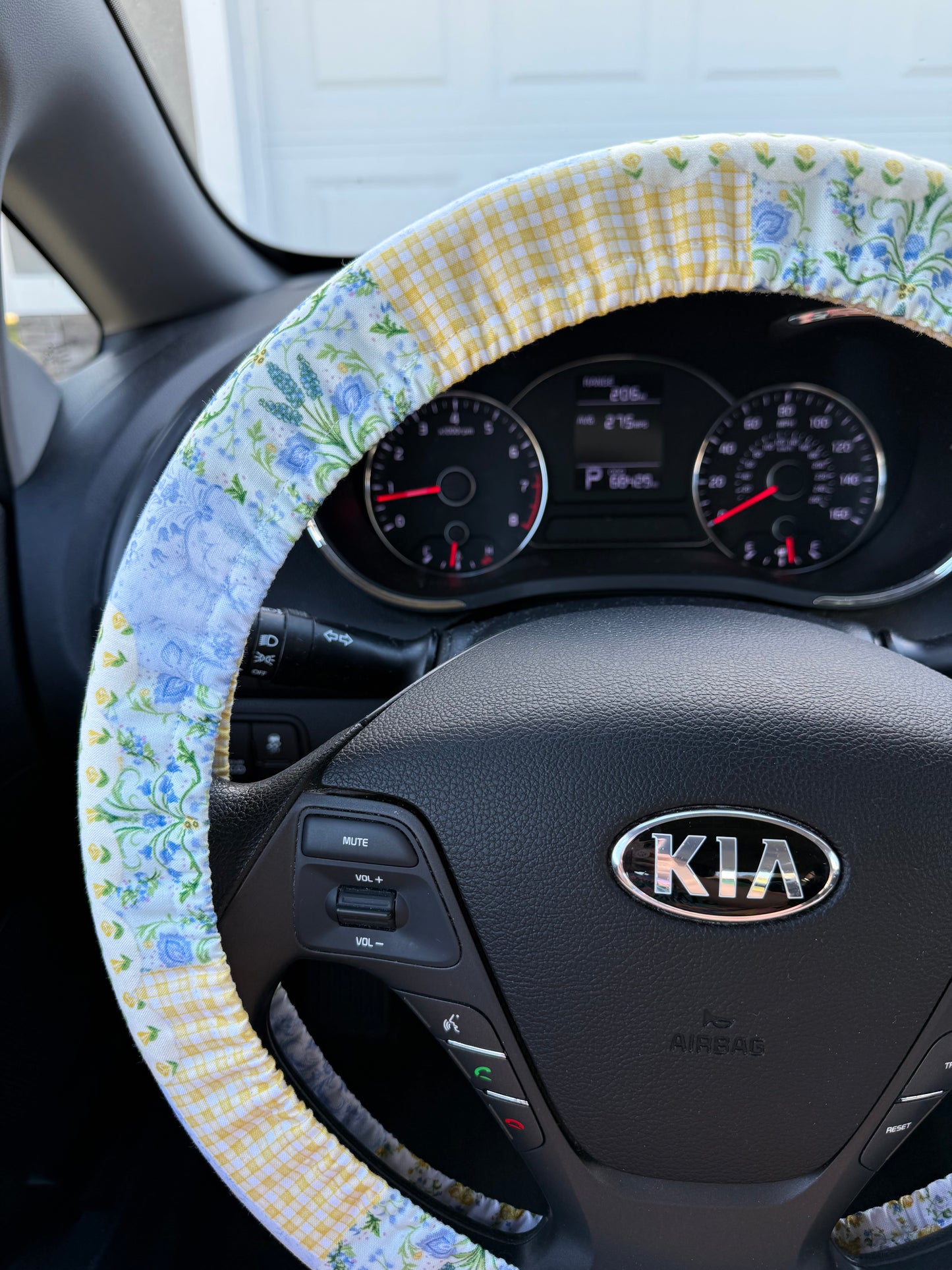Steering wheel of a Kia car with a floral steering wheel cover left side view