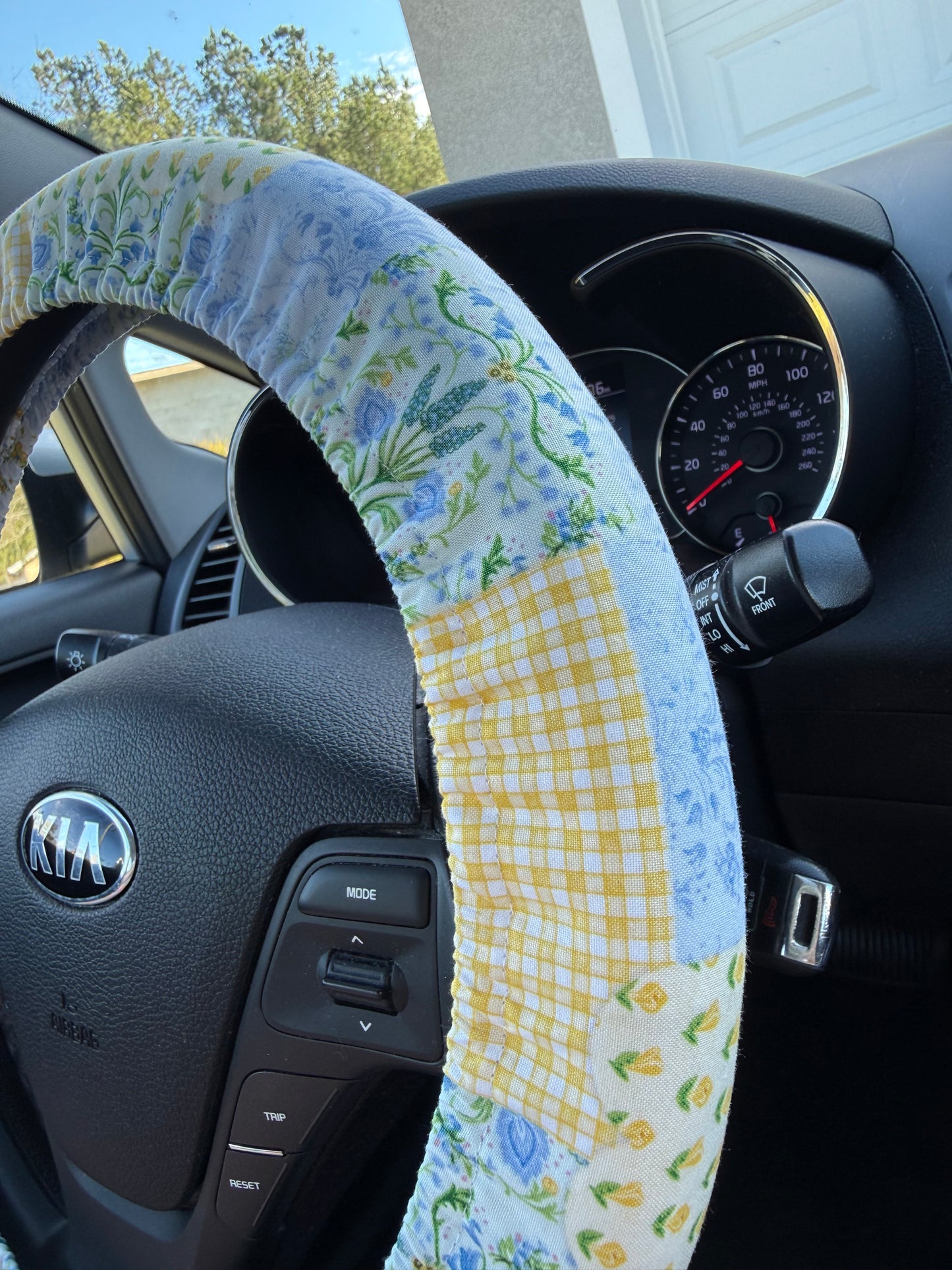 Steering wheel cover with floral and checkered patchwork pattern on a car steering wheel