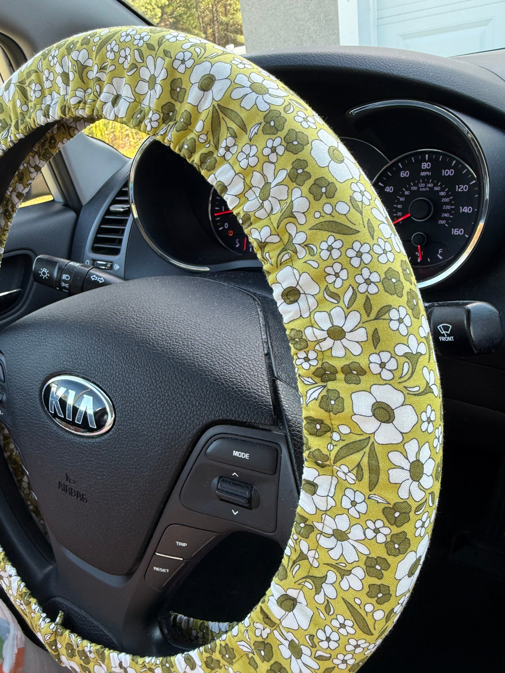 Steering wheel with a green floral steering wheel cover on Kia steering wheel showing a tilted view