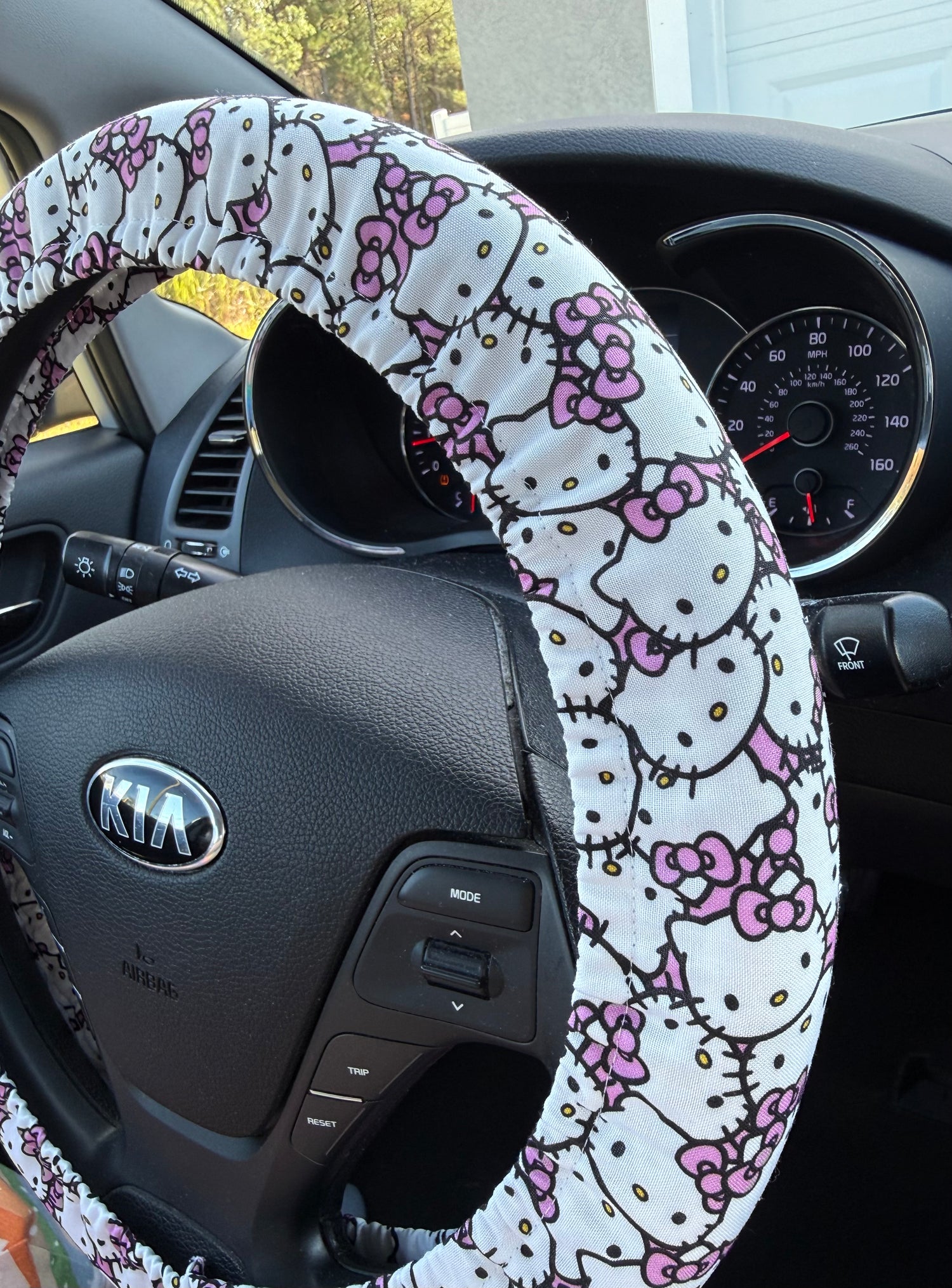 Steering wheel cover with Hello Kitty design on a Kia car steering wheel