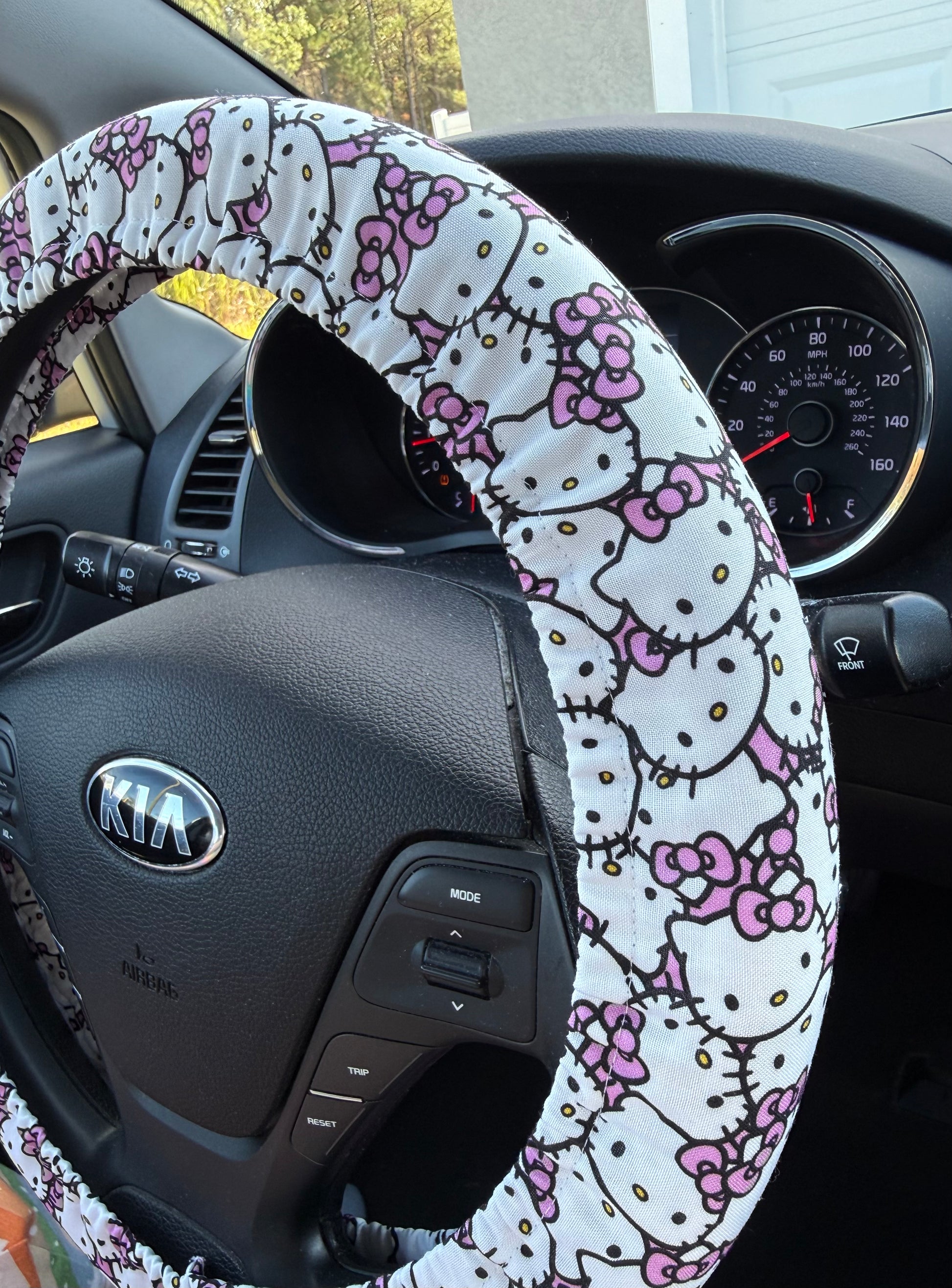 Steering wheel cover with Hello Kitty design on a Kia car steering wheel