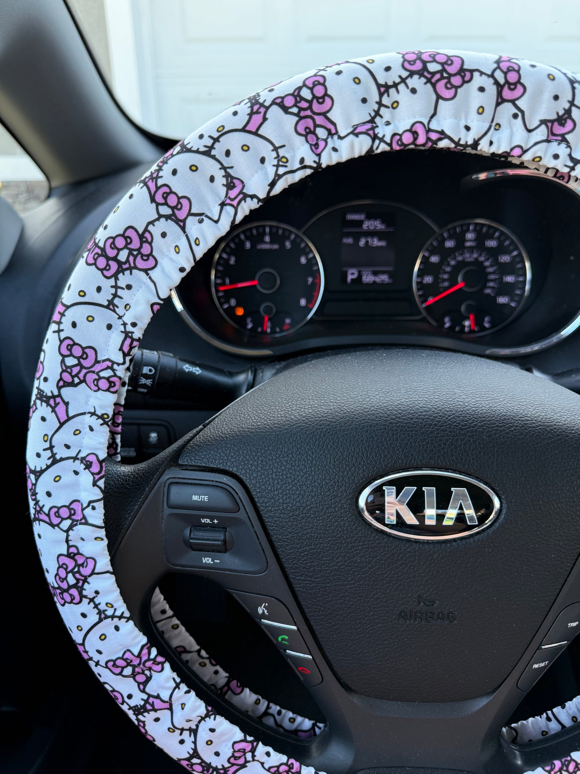 Car interior with a handmade steering wheel cover featuring a Hello Kitty pattern left side view