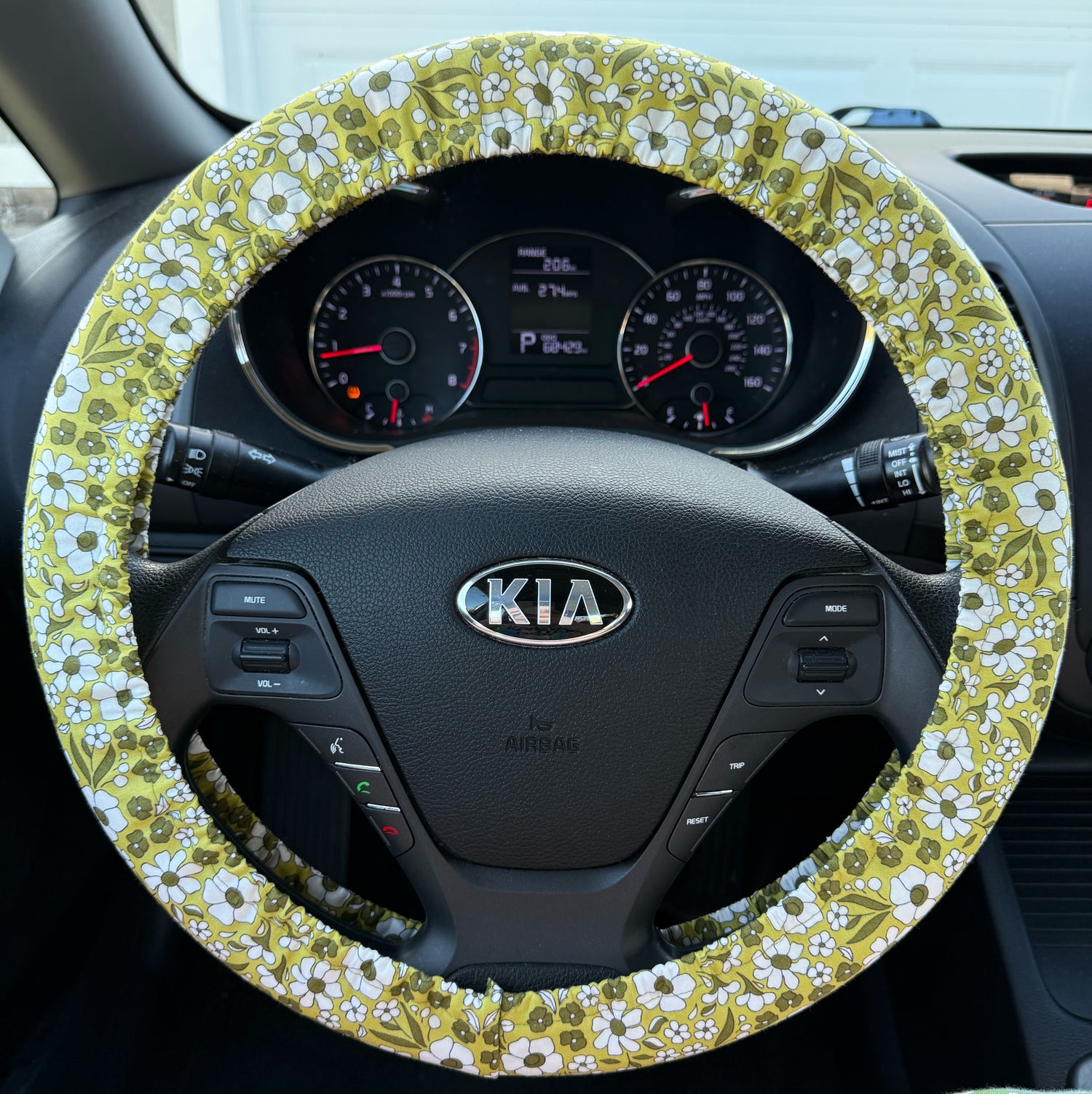 Green floral patterned steering wheel cover on a Kia car steering wheel front view