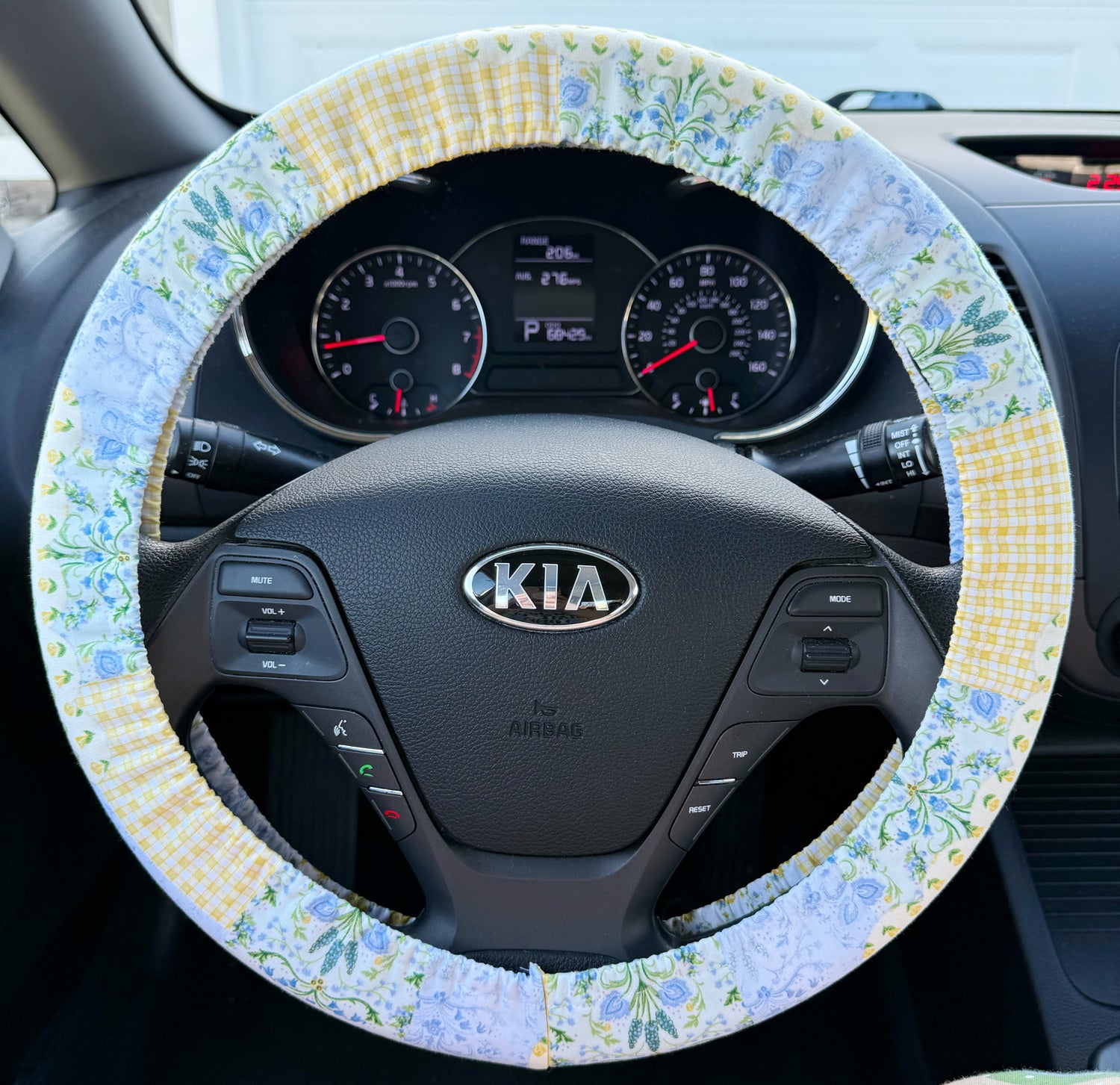 Floral blue and yellow patchwork steering wheel cover on a Kia car steering wheel